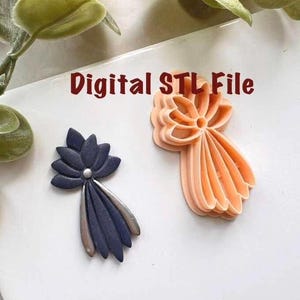 以下が含まれることがあります： 2つの花の形をした装飾品。1つはネイビーブルーにシルバーのアクセント、もう1つはピーチ色です。画像には「Digital STL File」というテキストが含まれています。オブジェクトは、背景に緑の葉がある白い表面にあります。