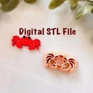 Puede incluir: Dos objetos con forma de cangrejo, uno rojo y otro color melocotón, se muestran sobre una superficie blanca. El texto "Digital STL File" está escrito en letras marrones encima. Probablemente archivos de impresión 3D.