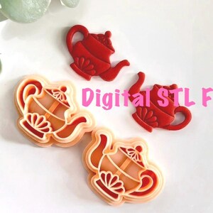 May include: Several red and orange teapot-shaped objects are arranged on a white surface. The objects are likely cookie cutters or molds, with intricate details. The text "Digital STL File" is superimposed on the image in pink.