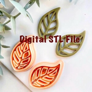 Könnte beinhalten: Bild von blattförmigen 3D-Druckformen. Zwei Formen sind orange und weiß, und zwei sind olivgrün. Die Formen befinden sich auf einer weißen Oberfläche. Der Text "Digital STL File" befindet sich in der Mitte des Bildes.