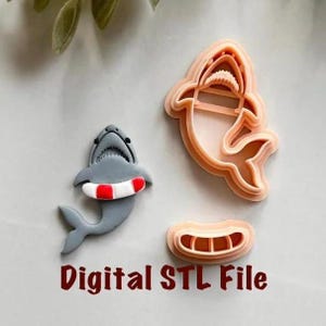 Peut inclure: Image de découpoirs à biscuits sur le thème des requins et d'une décoration en forme de requin. Les découpoirs à biscuits en forme de requin ont la forme d'un requin avec une bouche ouverte et d'un requin avec une bouée de sauvetage. Le texte "Digital STL File" est en bas.