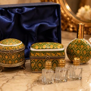 May include: A collection of vanity items including a round lidded box, a rectangular lidded box, and a spherical perfume bottle, all featuring a green and gold damask pattern. Three small, clear glass perfume vials with gold caps are included.