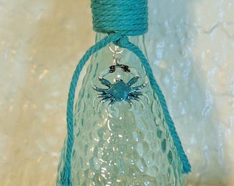 Botella verde claro con cangrejo y ribete color turquesa.