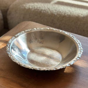 Peut inclure: Un bol rond et peu profond en argent avec une surface intérieure polie et réfléchissante, doté d'un bord festonné décoratif présentant un motif en relief répété. Le métal présente de légères rayures de surface dues à l'usage.