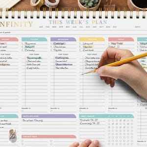May include: A weekly planner with a spiral binding, featuring the text "INFINITY" and "THIS WEEK'S PLAN". It includes sections for each day, a notes area, and a habit tracker. A hand is writing on the planner with a pencil.