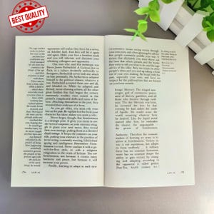 Op de afbeelding: Open boek met tekst op twee tegenover elkaar liggende pagina's. De linkerpagina heeft tekst en een rood en gouden "Best Quality"-sticker. De rechterpagina heeft tekst en een kleine afbeelding.