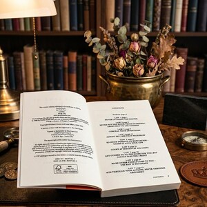 Op de afbeelding: Een open boek met de inhoudsopgave zichtbaar, met teksten over wetten en strategie&euml;n. Een messing pot met gedroogde bloemen staat achter het boek. Een kompas en munten liggen ook op het houten oppervlak.