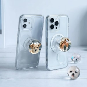 May include: Clear phone cases with attached photo phone grips. One grip features a dog, the other a couple. Two additional clear grips with dog faces are also visible.