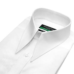 May include: A crisp white long-sleeve dress shirt featuring a sharp, pointed collar and a button-down front. The inner neck label displays the text John Clothier London Green Label. The fabric has a subtle, fine-textured weave throughout the garment.