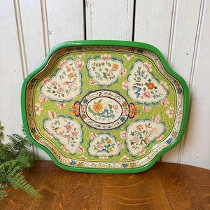 May include: A vintage decorative tray with a green scalloped edge. The tray features a light green background with floral and bird designs in pink, orange, and blue. An oval floral design is in the center.
