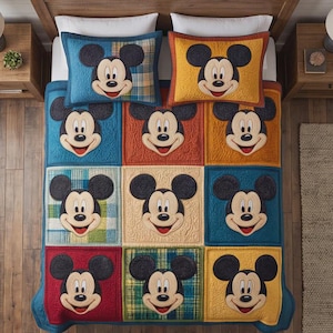 Op de afbeelding: Een kleurrijke patchwork quilt en twee bijpassende kussenslopen met Mickey Mouse. De quilt toont een raster van vierkanten in verschillende kleuren, elk met een Mickey Mouse gezicht. De kussens hebben een vergelijkbaar ontwerp.