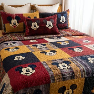 May include: A patchwork quilt and pillow set featuring Mickey Mouse. The quilt and pillows have a variety of colors including red, yellow, and navy blue. The quilt is made up of squares with Mickey Mouse's face embroidered on them. The pillows have Mickey Mouse's face on them.