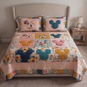 May include: A quilted bedspread and two pillow shams featuring a Mickey Mouse design. The quilt has a patchwork design with floral and solid squares in pink, yellow, and blue. The pillow shams have a Mickey Mouse head design in the center.