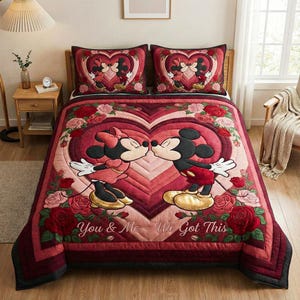 May include: A red and pink quilted bedspread featuring Mickey and Minnie Mouse kissing inside a heart-shaped design. The bedspread includes two matching pillowcases. The words "You & Me - We Got This" are stitched on the bedspread.