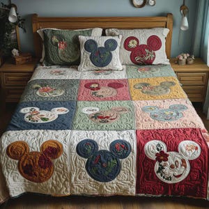 Puede incluir: Un juego de edred&oacute;n y almohadas de patchwork con dise&ntilde;os de Mickey Mouse. El edred&oacute;n y las almohadas tienen un patr&oacute;n acolchado con cabezas de Mickey Mouse en varios colores, incluyendo rojo, azul, verde y amarillo. Bordados florales acent&uacute;an los dise&ntilde;os. El juego de cama est&aacute; sobre una cama de madera.