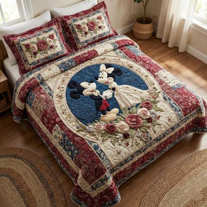 Puede incluir: Un edredón acolchado y dos fundas de almohada con Mickey y Minnie Mouse. El edredón tiene un círculo azul central con los personajes, rodeado de patrones florales y geométricos en rojo, crema y azul. Las fundas de almohada tienen diseños florales.