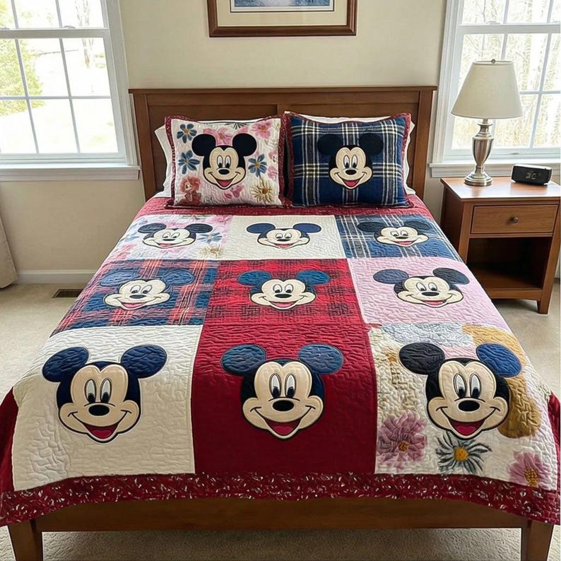 Peut inclure: Une courtepointe patchwork et deux coussins assortis avec Mickey Mouse. La courtepointe a une palette de couleurs rouge, blanche et bleue avec divers motifs et visages de Mickey Mouse. Les coussins ont des motifs floraux et &agrave; carreaux.