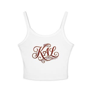May include: White crop top with thin straps. The top features the word "KAL" in a decorative, brown script across the front. The design includes swirls and flourishes, adding a touch of elegance to the casual garment.