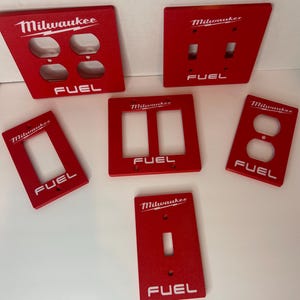 May include: A white ceramic mug with a black handle and the text "But First, Coffee" in a bold, black font. The mug is set against a blurred background, suggesting a cozy setting.