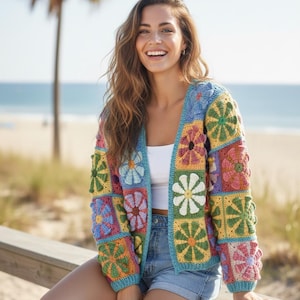 May include: A colorful, open-front crochet cardigan with a floral patchwork design. The jacket features squares of various colors, including blue, yellow, pink, and green, with white flower details. The cardigan is worn with a white top and denim shorts.