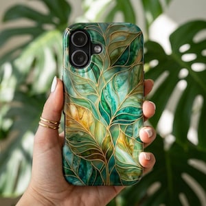 May include: A smartphone case with a vibrant, nature-inspired design. The case features a pattern of green and gold leaves with intricate gold outlines. The glossy finish enhances the colors, creating a stylish accessory.