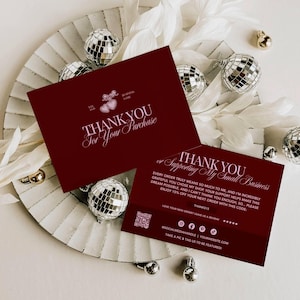 May include: Two rectangular dark red thank you cards with white text. One card reads "THANK YOU For Your Purchase" with a heart icon. The other card reads "THANK YOU Supporting My Small Business" with a discount code, social media icons, and a QR code.