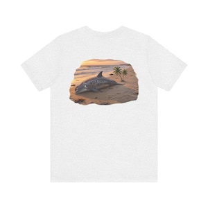 May include: Light gray t-shirt featuring a graphic of a dolphin on a beach at sunset. The dolphin has the text "404 Something Went Wrong" printed on its side. Palm trees and ocean waves are visible in the background.