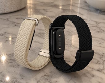 May include: Two braided watch bands for a fitness tracker, one in cream and one in black. The cream band features a silver-toned metal buckle and connector, while the black band includes a black plastic sensor housing and a matching black magnetic clasp.