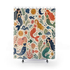 May include: A shower curtain featuring a repeating pattern of mermaids with long flowing hair in various colors, interspersed with illustrations of suns, moons, stars, seashells, fish, and seaweed on a light cream-colored background.