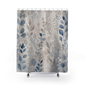 May include: A shower curtain featuring a watercolor-style botanical print with various blue and grey leaves, stems, and sprigs arranged vertically against a neutral, light beige background. The design includes silver-toned metal grommets at the top.