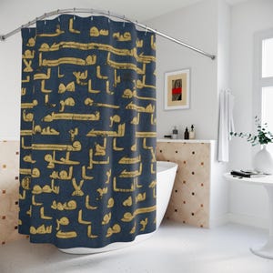 May include: A navy blue shower curtain featuring a repeating pattern of gold Arabic script. The curtain is displayed in a bathroom with a white bathtub and a small framed artwork. The curtain is made of a soft, durable material.