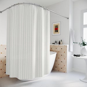 May include: A white shower curtain with vertical dashed lines in a light gray color. The curtain hangs from a curved, silver-colored shower rod. The bathroom has a white bathtub, a small table, and a framed piece of art.