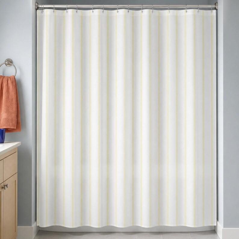Pale yellow pinstripe shower curtain in a blue-gray bathroom with maple vanity and terracotta towel