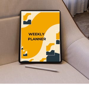 Peut inclure: Une tablette noire affichant un design "WEEKLY PLANNER" avec des formes abstraites jaunes et bleu marine. Un stylet blanc est posé en dessous sur une surface de ton neutre. La tablette est sur une chaise beige.