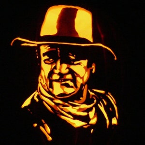 May include: A carved pumpkin depicting a person wearing a hat and a scarf. The pumpkin is lit from the inside, creating a warm glow.