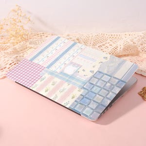 May include: A laptop protective case featuring a collage design with pastel pink and blue gingham patterns, vertical floral stripes, and a grid of light blue square tiles. The surface displays a mix of soft textures and delicate botanical motifs.