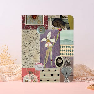 May include: A rectangular notebook cover featuring a collage of various illustrations including a central figure with a white flower, a cat, a table setting, a heart-shaped lock, and a small label with the word Here printed in black script.