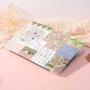 May include: A laptop skin featuring a collage of patterns including green gingham, pink floral prints, a light green bow, a blue botanical design, and a central illustration of a person in a room with framed art and a sleeping cat on a bed.