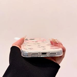 A bottom edge view shows the clear Hello Kitty phone case with the charging port and speaker cutouts visible.