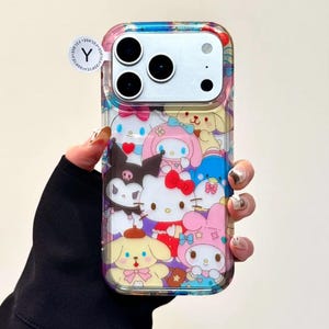 May include: Clear phone case featuring a colorful collage of cartoon characters, including Hello Kitty and friends. The case has a transparent border and a multi-colored design on the top. A small, circular sticker with the letter "Y" is visible.