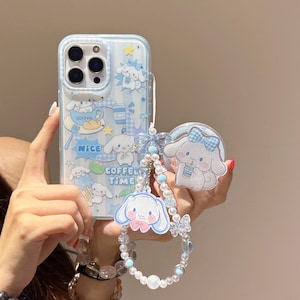 Può includere: Custodia per telefono azzurra con un design di personaggi dei cartoni animati, con un cinturino da polso abbinato con perline e ciondoli. La custodia ha un motivo a righe e le parole "coffee time".