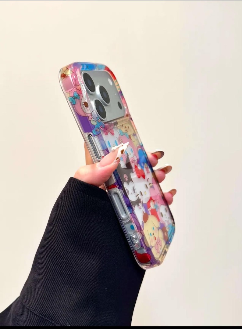 May include: Clear phone case featuring a colorful cartoon character design. The case has a transparent background with a vibrant pattern of various characters in shades of pink, blue, yellow, and purple. The case is designed to fit a smartphone.