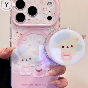 May include: Pink and clear phone case with a matching pop socket. The case features a cartoon bear design with strawberries and the text "Have a good day to you!" The pop socket has a cartoon bear chef design.