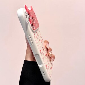 A side-profile view shows the thickness and buttons of the Hello Kitty case with the decorative back partially visible.