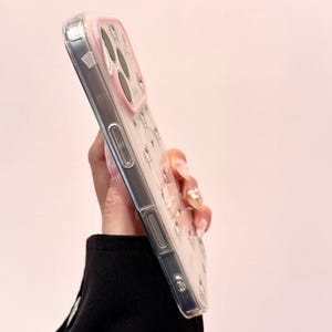 A side-profile view shows the clear Hello Kitty phone case edge and buttons from the side.