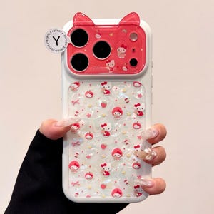 A close front view shows the Hello Kitty case with the red cat-ear camera cover and patterned pearly back.