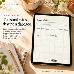 May include: A digital tablet displaying a Monthly Wins Wall planner page for January. The screen shows a grid calendar with text entries for daily financial achievements, navigation tabs, and the title January Wins. The text reads: The small wins deserve a place, too.