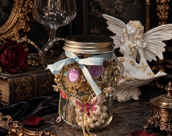 May include: A clear glass jar with a metal lid, filled with assorted jewelry including gold chains, white pearls, and purple cameos. A light blue ribbon is tied around the neck, and a pink and white butterfly-shaped brooch is attached to the front.