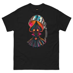 May include: A black short-sleeved t-shirt featuring a graphic print of a dark, hooded figure with glowing orange eyes, wearing a pleated cape with a red gem, positioned beneath a metallic, dome-shaped hair dryer hood with pink interior lighting.