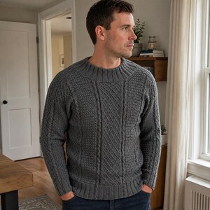 Può includere: Un maglione grigio antracite a maniche lunghe con girocollo, polsini e orlo a coste spesse. Il capo presenta un motivo a maglia testurizzato con colonne di trecce verticali e un design a punto grigliato sul davanti e sulle maniche.